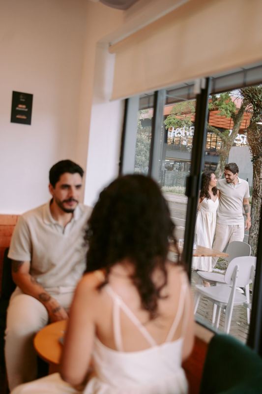 Casal conversando em uma cafeteria, vistos pela janela