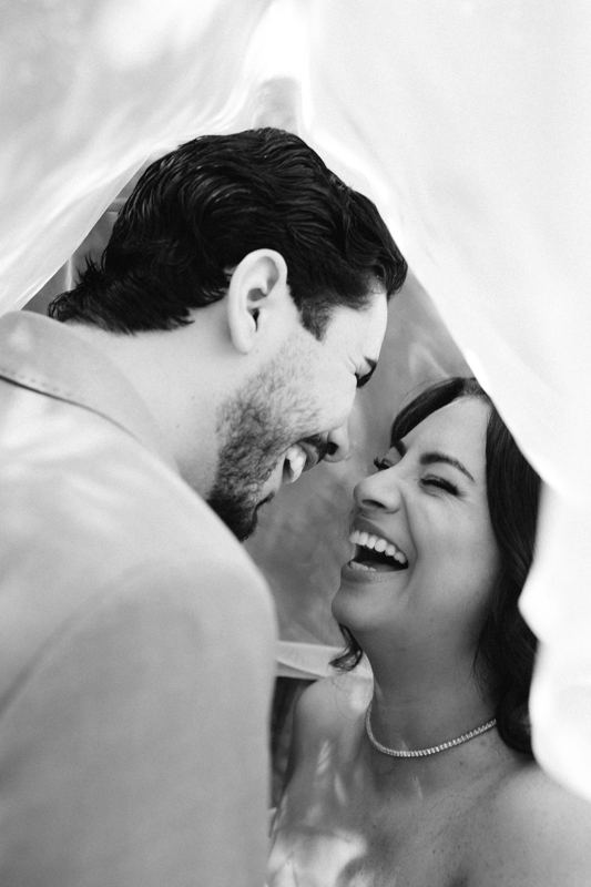 Casal rindo sob o véu, em preto e branco