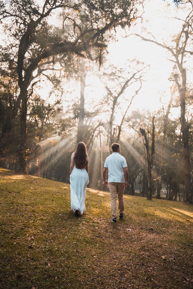 Casal caminhando entre árvores com raios de sol